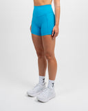 Side view of the Azure Blue Nexletica Synergy Rise Shorts showing the tonal NEXLETICA leg branding and side pocket