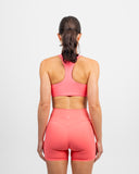 Back view of Nexletica Impulse High Neck Sports Bra in coral highlighting racerback and strap design