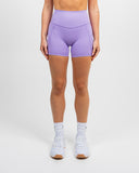 Front view of woman wearing lilac Nexletica Impulse High Waist Shorts 5 inch and matching sports bra